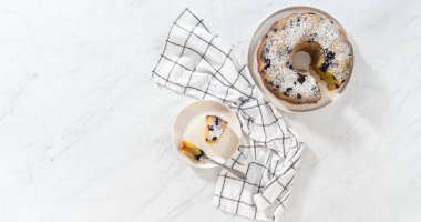 Düz yatıyordu. Taze pişmiş limonlu yaban mersinli kek dilimliyorum. Pudra şekerli..