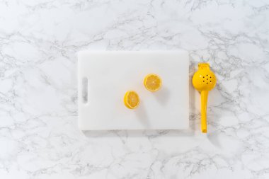 Beyaz bir kesme tahtasının üzerinde taze limon zıp zıp..