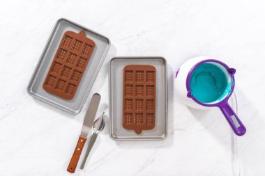 Düz yatıyordu. Çikolata kalıplarını erimiş çikolatayla doldurarak küçük denizkızı çikolatalarını hazırlıyorum..