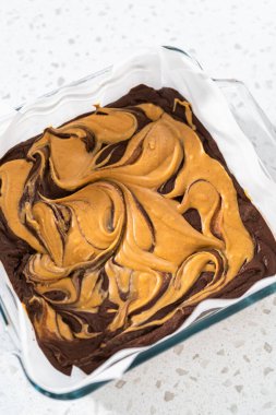 Removing chocolate fudge with peanut butter swirl from the baking pan lined with parchment