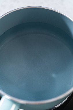 Çikolata parçacıkları ve diğer malzemeleri kaynayan suyun üzerinde karıştırarak çikolatalı şekerleme ve fıstık ezmesi karışımı hazırlıyorum..