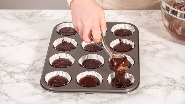 Step by step. Baking chocolate cupcakes. Scooping chocolate cupcake batter into a cupcake pan.