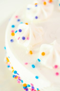 Beyaz kek tabağına funfetti serpiştirilmiş küçük beyaz doğum günü pastası.