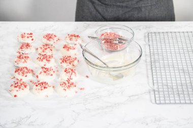 Naneli beyaz çikolatalı kurabiyeler hazırlamak için eritilmiş beyaz çikolataya çikolatalı kurabiyeler batırmak..