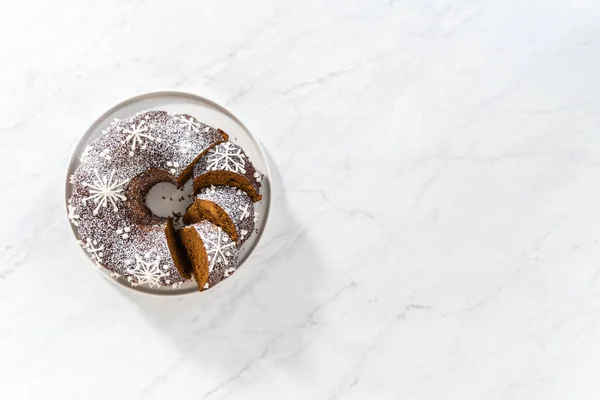 stock image Flat lay. Sliced gingerbread bundt cake with caramel filling, buttercream frosting, and powdered sugar dusting on the cake plate.