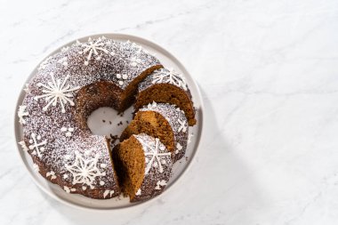 Dilimlenmiş zencefilli kek karamel dolgulu, kremalı pasta ve kek tabağında toz şeker..