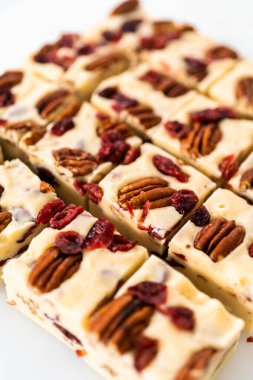 Beyaz çikolatalı fındıklı fındıklı şekerlemeyi beyaz bir kesme tahtasında küçük parçalara ayırmak..