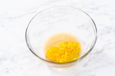 Lemon Cookies with White Chocolate. Mixing wet ingredients in a large glass mixing bowl to bake lemon cookies with white chocolate.
