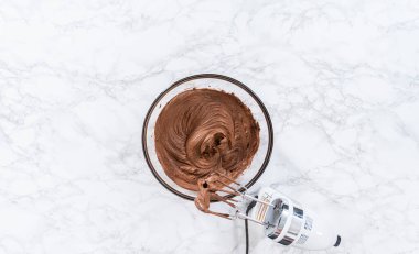 Düz yatıyordu. Marketten alınmış çikolatalı şekerlemeyi karıştırıyorum cam kaseyle karıştırıyorum..