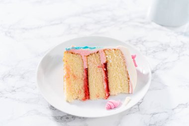 Deniz kızı temalı 3 katlı vanilyalı pasta dilimi. Çikolatalı deniz kızı kuyruğu ve beyaz tabakta deniz kabukları..