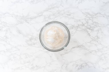 Düz yatıyordu. Limonlu haşhaş tohumlu kek pişirmek için bardakta çırpma kabıyla kuru malzemeyi karıştırıyorum..