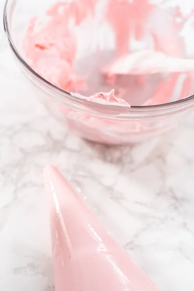 厨房八分仪上的管道袋里冒着粉红色的奶油霜 — 图库照片