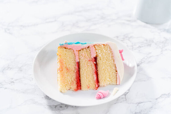 Slice of a mermaid-themed 3 layer vanilla cake with chocolate mermaid tails and seashells on a white plate.