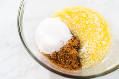 Beyaz çikolatalı macadamia fındığı pişirmek için ıslak malzemeleri büyük bir bardakta karıştırıyorum..