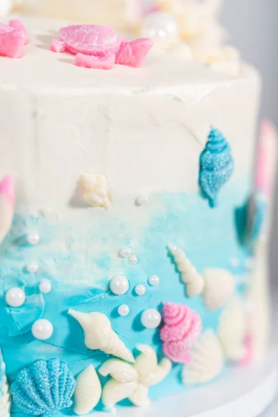以美人鱼为主题的三层香草蛋糕 装饰有巧克力美人鱼尾巴和调味品 放在一个白色的蛋糕架上 — 图库照片