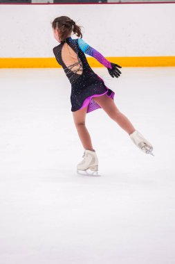 Küçük kız buz pateni pistinde artistik buz pateni yarışmasından önce pratik yapıyor..