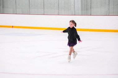 Küçük kız buz pateni pistinde artistik buz pateni yarışmasından önce pratik yapıyor..