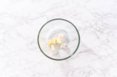 Flat lay. Mixing ingredients in a large glass mixing bowl to prepare cream cheese drizzle sauce.