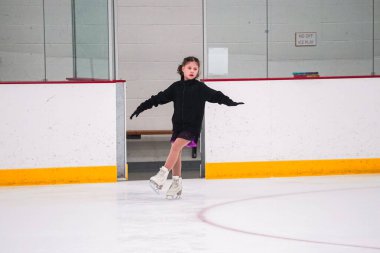 Küçük kız buz pateni pistinde artistik buz pateni yarışmasından önce pratik yapıyor..