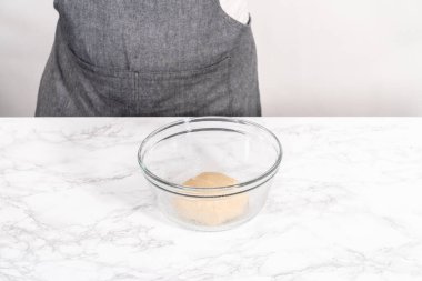 Tarçınlı tatlı pizzası hazırlamak için cam bir kasede pizza hamuru yetiştiriyorum..