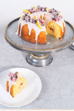 Dilimlenmiş limonlu kek. Şeker kızılcıkları ve limon dilimleri ile süslenmiş..