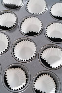 Scooping cupcake batter with dough scoop into a baking pan with liners to bake American flag mini cupcakes.
