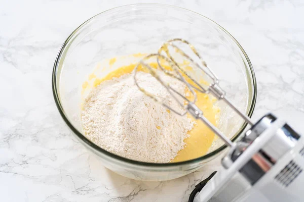 将配料和手搅拌器混合在一个大的搅拌碗里 用米黄色粉红奶油糖霜烤小香草杯蛋糕 — 图库照片