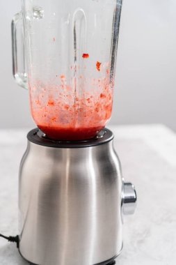 Çilekli kremayı hazırlamak için mutfak blendırında taze çilek harmanlıyorum..