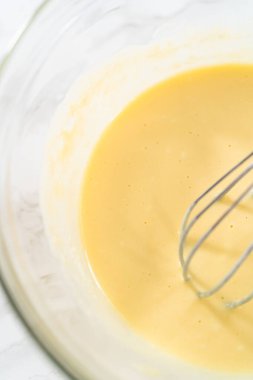 Küçük bir bardakta ıslak malzemeler karıştırmak mini vanilyalı kekler pişirmek için ombre pembe tereyağlı krema.