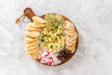 Düz yatıyordu. Sebzeli tereyağı tahtası ve tahta kesme tahtasında ekmek..