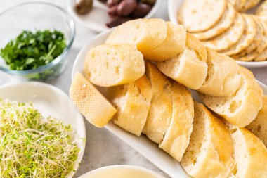 Tereyağı tahtasını sebze ve ekmekle karıştırmak için cam kaselerde ölçülmüş malzemeler..