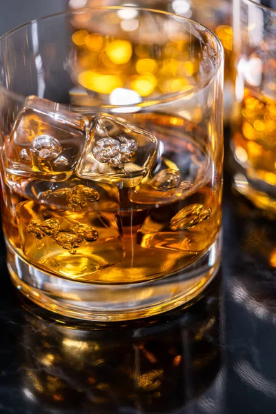 stock image Scotch on the rocks in whiskey glass on a black marble surface.