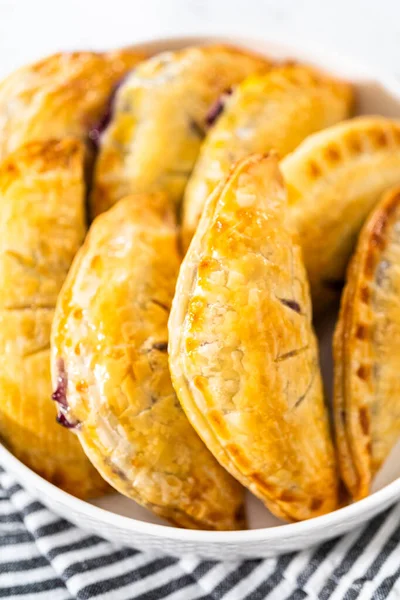 stock image Freshly baked sweet empanadas with blueberries on the kitchen counter.