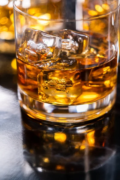 stock image Scotch on the rocks in whiskey glass on a black marble surface.