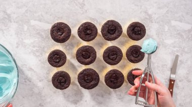 Düz yatıyordu. Adım adım. Çikolatalı keklerin üstüne mavi tereyağlı krema sürüyorum..