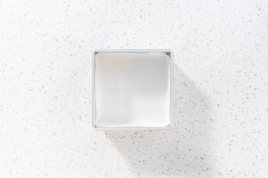 Düz yatıyordu. Çikolatalı şam fıstıklı şekerleme hazırlamak için parşömen kağıdıyla kare çizgili cheesecake tavası..