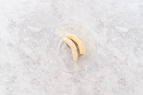 ココナッツバナナパンケーキを準備するためにガラス混合ボウルに揚げバナナを粉砕 — ストック写真