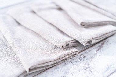 Ahşap beyaz bir masada doğal renkte keten bir peçetenin yakın görüntüsü..