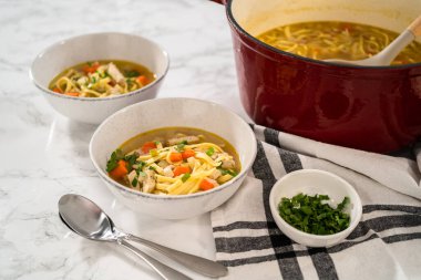 Beyaz seramik çorba kaselerinde kluski şehriyeli tavuk çorbası servis ediyorum..