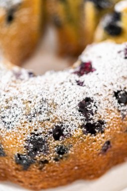 Taze pişmiş limonlu yaban mersinli kek dilimliyorum. Pudra şekerli..