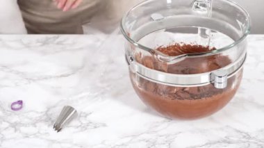 Zaman aşımı. Çukulata renginde ganache kreması, metal uçlu bir torbaya konuyor..