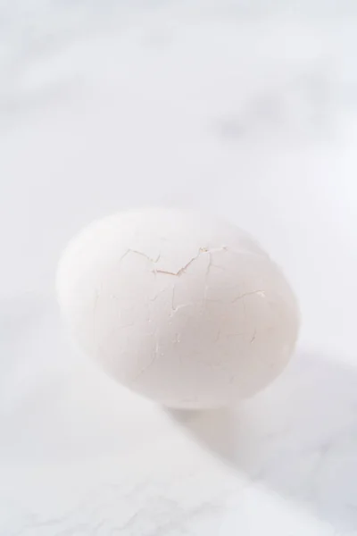 大理石のキッチンカウンターでゆで卵の皮をむく — ストック写真