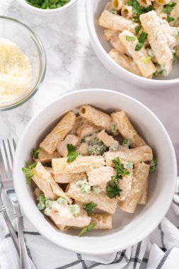 Küçük bir kasede yeşil bezelyeli tavuk ve rigatoni makarna..