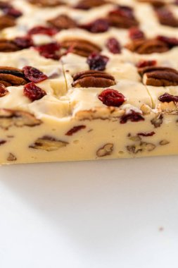 Beyaz çikolatalı fındıklı fındıklı şekerlemeyi beyaz bir kesme tahtasında küçük parçalara ayırmak..