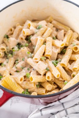 Alfredo soslu tavuk pişirmek için mayalı bir fırının içindekileri karıştırıyorum..