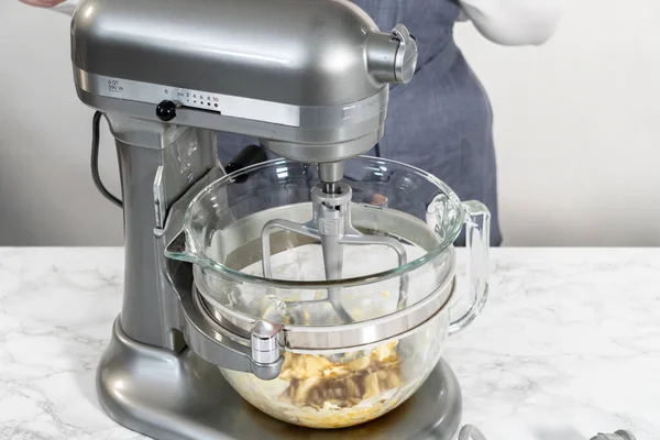 Mixing ingredients in a kitchen stand mixer to bake soft oatmeal raisin walnut cookies.