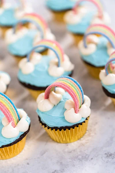 ブルーバタークリームのフリスティングとユニコーンのテーマの誕生日パーティーのための虹で飾られたチョコレートカップケーキ — ストック写真