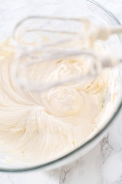 Krem peynirli krema hazırlamak için büyük bir bardakta karıştırma malzemeleri..