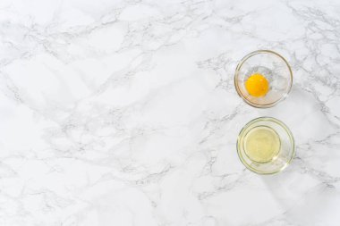 Flat lay. Separating egg whites and egg yolks into small bowls.