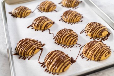 Muzlu kurabiyelerin üzerine erimiş çikolata serpiştirmek.